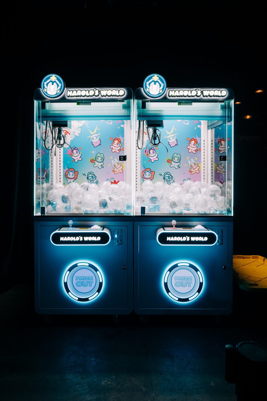 Two Harold's World branded claw machines with lit marquees, character backdrops, and custom control panels