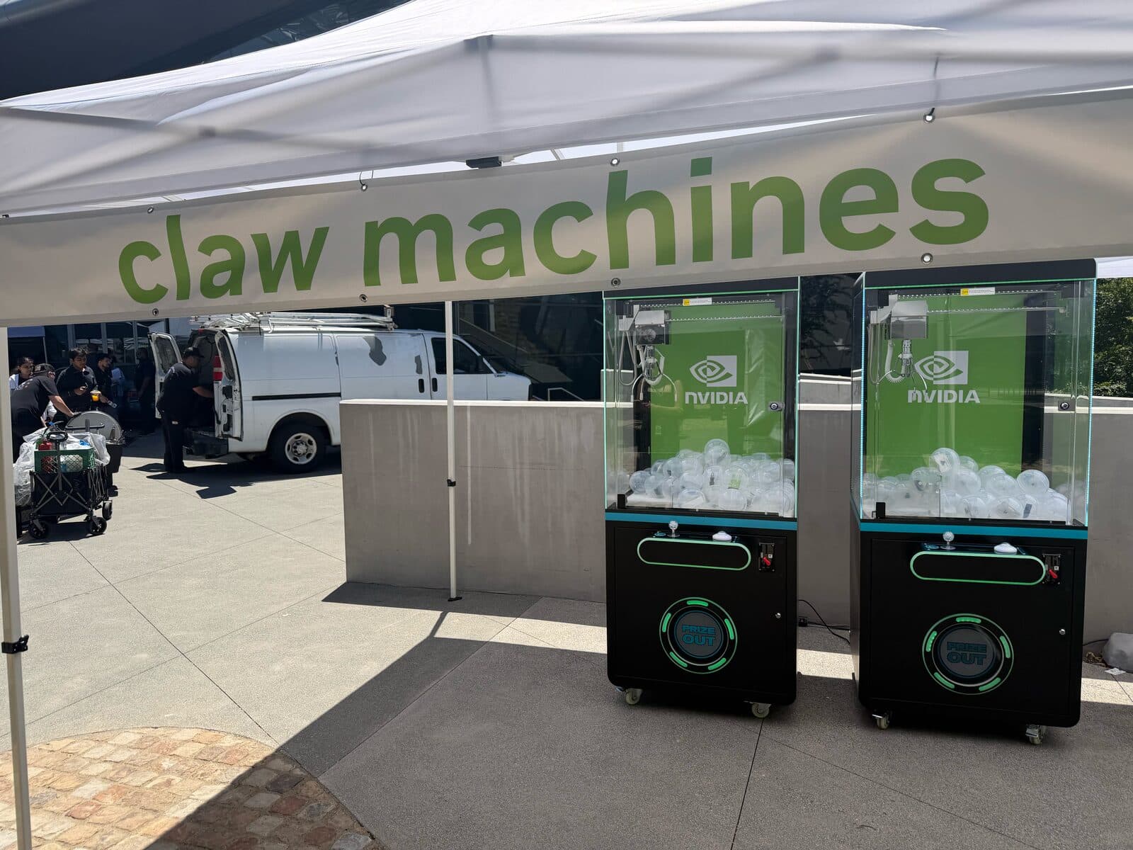 Two NVIDIA branded claw machines under a claw machines tent at an outdoor corporate event
