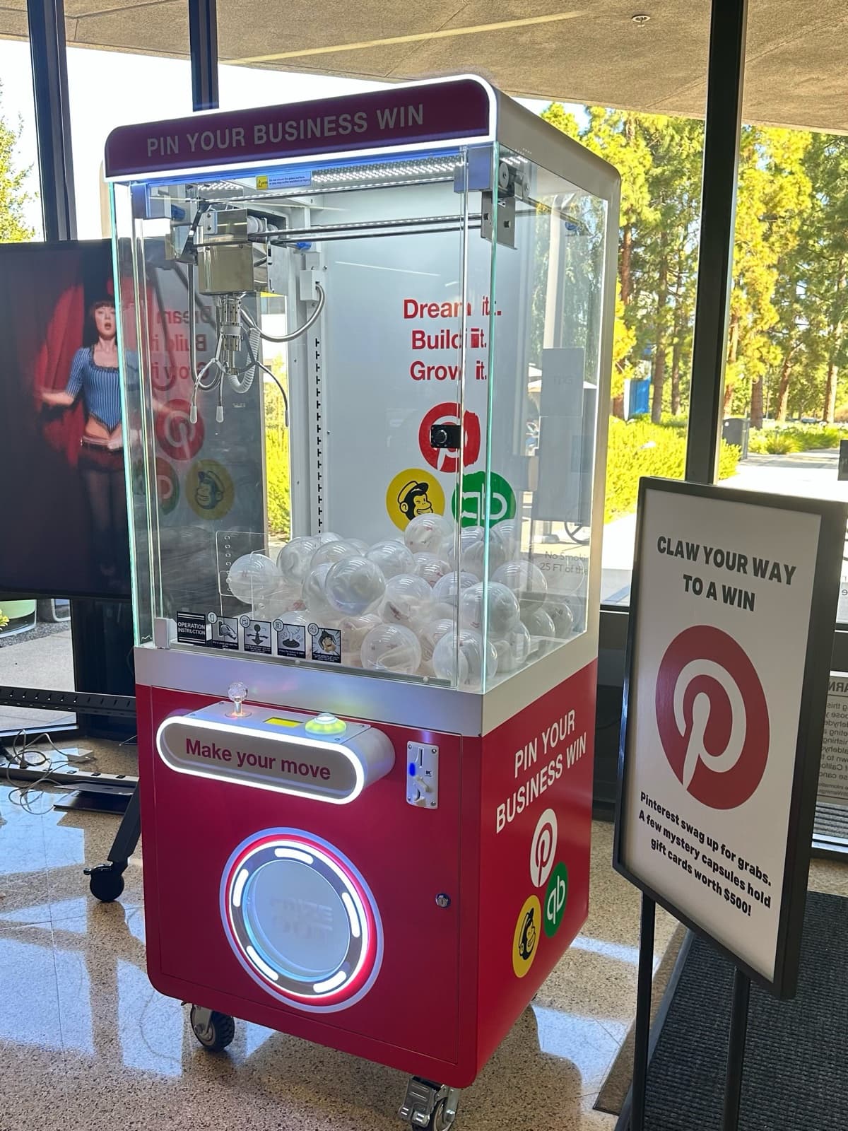 Pinterest branded red claw machine with lit Pin Your Business Win marquee and Dream it. Build it. Grow it. backdrop at a corporate event on the Intuit campus in Mountain View